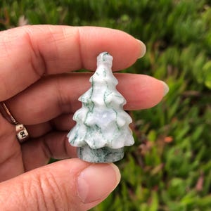 May include: A small, white and green carved agate tree ornament. The tree is carved in a simple, traditional style with a rounded top and a few branches.
