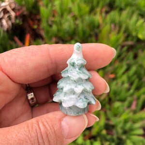 May include: A small, green and white carved jade tree ornament. The tree is about 2 inches tall and has a detailed, realistic design.