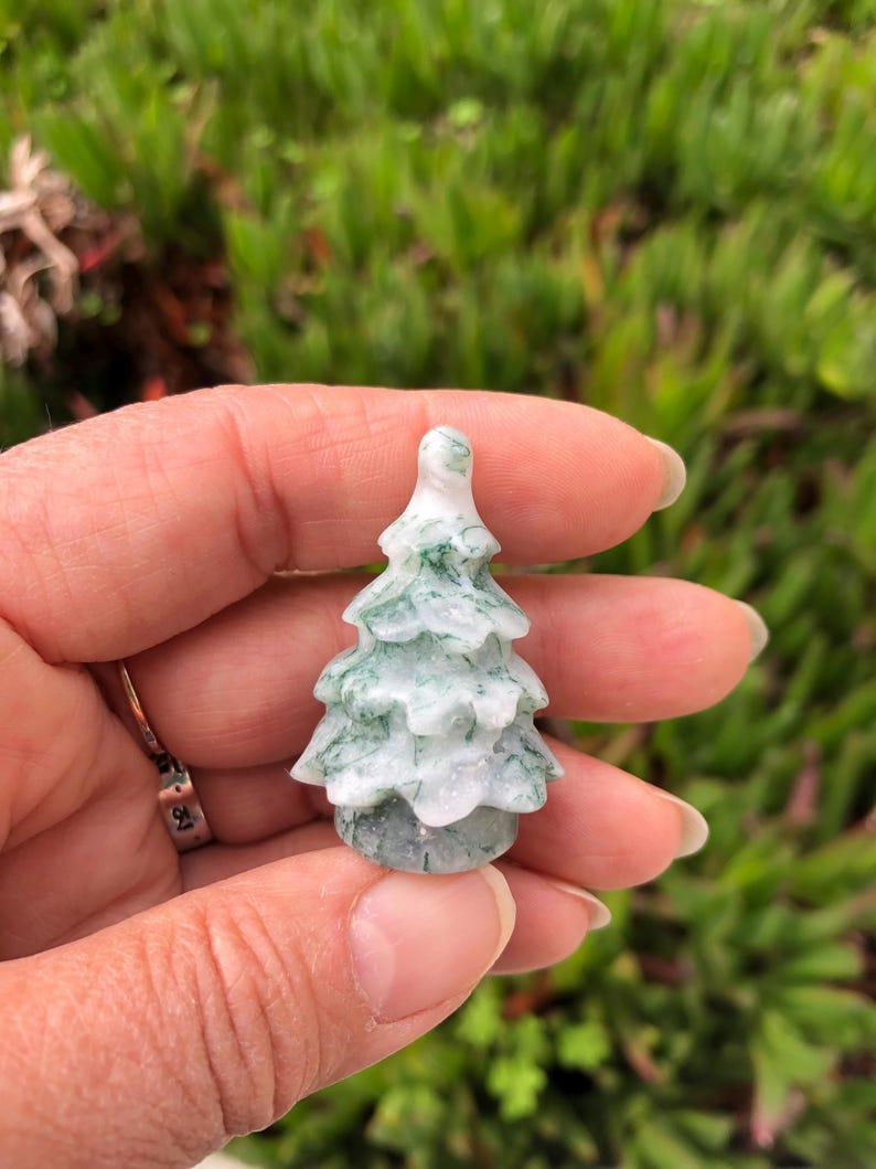 May include: A small, carved green and white agate tree ornament. The tree is about 2 inches tall and has a detailed, realistic design.