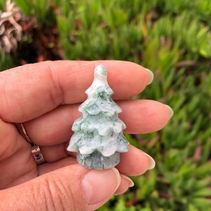 May include: A small, carved green and white jade tree ornament. The tree is about 2 inches tall and has a detailed, realistic design.