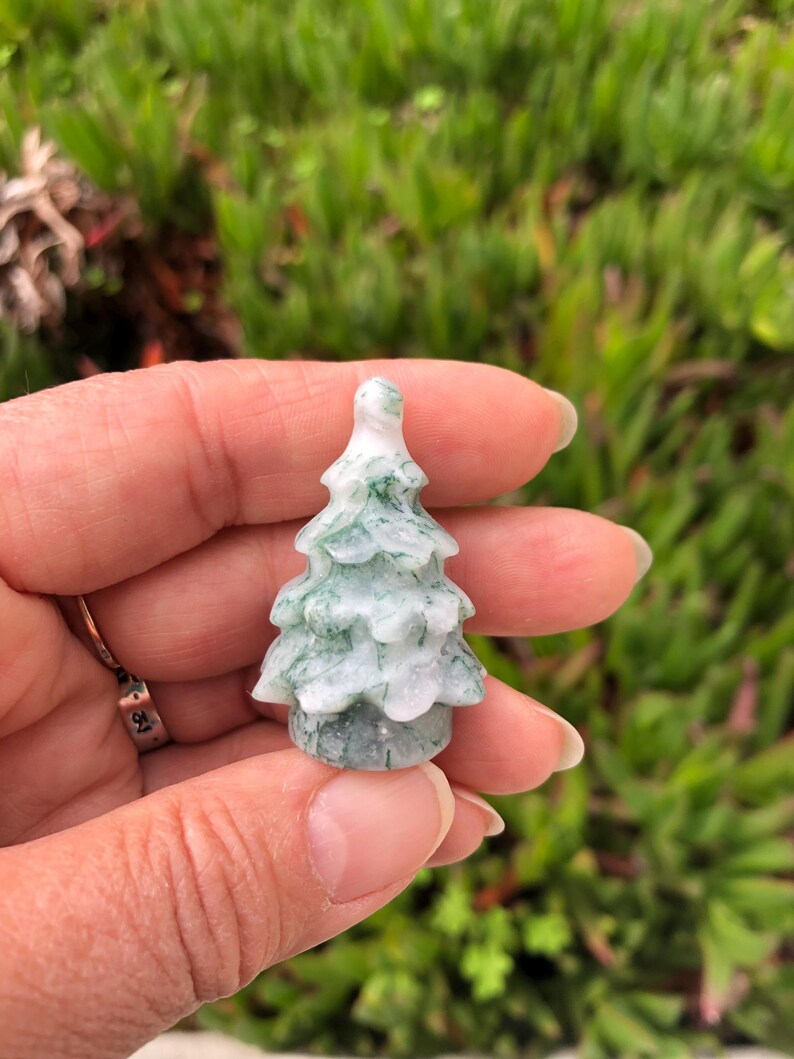 May include: A small, carved green and white jade tree ornament. The tree is about 2 inches tall and has a detailed, realistic design.