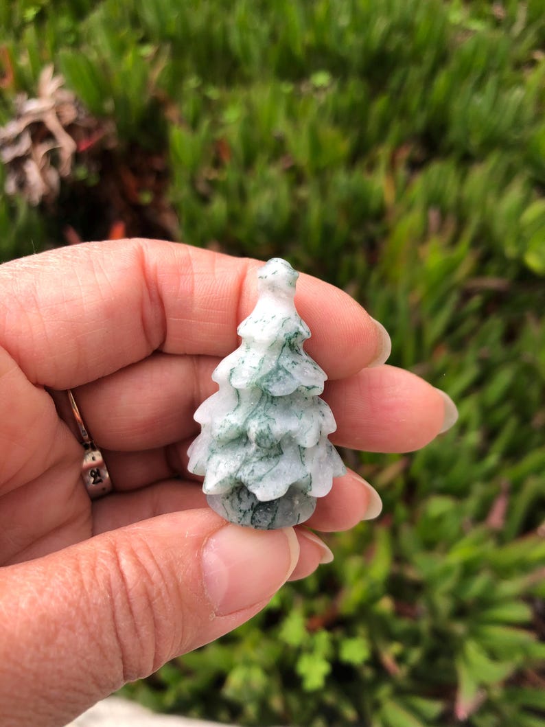 May include: A small, carved green and white agate tree ornament. The tree is about 2 inches tall and has a detailed, realistic design.