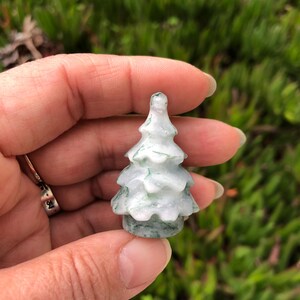 May include: A small, carved green and white jade tree figurine. The tree is about 2 inches tall and has a detailed, realistic design.