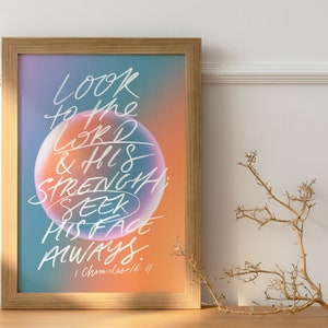 Puede incluir: Una impresión artística enmarcada con un fondo degradado de azul, naranja y morado. La escritura blanca en script dice "Look to the Lord & His Strength; Seek His Face Always." El marco es marrón claro.