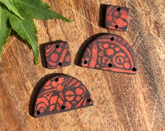 May include: Four ceramic tile shapes with a black and red geometric pattern. The tiles are in the shape of a square, a half-circle, and two quarter-circles.