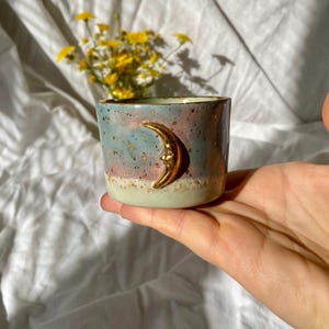 Taza de porcelana hecha a mano con forma de media luna, cerámica artesanal en tonos pastel, taza de café con detalles dorados.