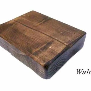 May include: A rectangular wooden block with a dark walnut stain. The wood grain is visible and the edges are rounded. The block is sitting on a white background. Walnut.