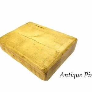 May include: A rectangular block of wood with a light yellow finish. The wood has a natural grain pattern and is labeled "Antique Pine".