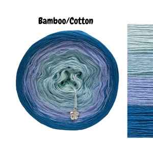 May include: A skein of blue, green and purple ombre yarn made of bamboo and cotton. The yarn is wound into a ball and has a silver flower charm attached.