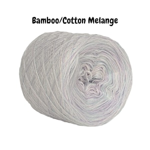 May include: A skein of light gray yarn with a subtle, variegated pattern. The yarn is labeled "Bamboo/Cotton Melange".