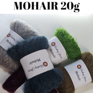 May include: Five skeins of mohair yarn in different colours: grey, teal, green, brown, and burgundy. Each skein is labelled "Fantasy Yarn Mohair 20g".
