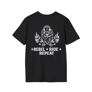 Op de afbeelding: Zwart t-shirt met een witte afbeelding van een motorrijder met een bril en bandana, geflankeerd door vlammen en gereedschap. De tekst "REBEL RIDE REPEAT" staat eronder, met sterren aan weerszijden. Een casual t-shirt voor motorliefhebbers.