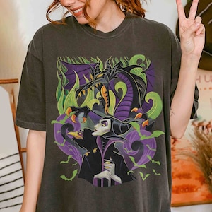 K&ouml;nnte beinhalten: Ein dunkelgraues T-Shirt mit einem Grafikdruck von Maleficent aus dem Disney-Film Dornr&ouml;schen. Die Grafik zeigt Maleficent mit ihrer Drachenform, einem Raben und Flederm&auml;usen.