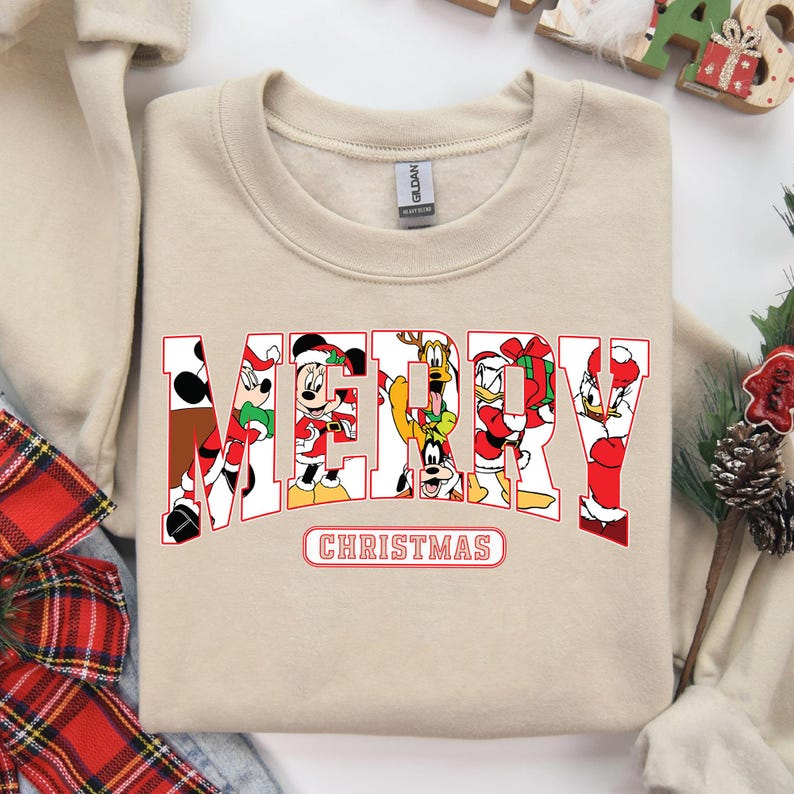 May include: A beige sweatshirt with a red and white "Merry Christmas" graphic featuring Mickey Mouse, Minnie Mouse, Donald Duck, Goofy, and Pluto.