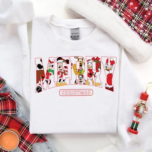 May include: White Christmas sweatshirt with a red "Merry Christmas" graphic featuring Mickey Mouse, Minnie Mouse, Donald Duck, Goofy, and Pluto.