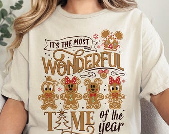 Könnte beinhalten: Ein beiges T-Shirt mit einem weihnachtlichen Design mit Lebkuchenfiguren von Disney. Der Text auf dem Shirt lautet "It's the most wonderful time of the year".