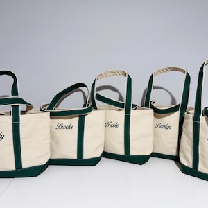 May include: Five canvas tote bags with green trim and personalized names: Kelly, Brooke, Nicole, Katelyn, and Kelsey.