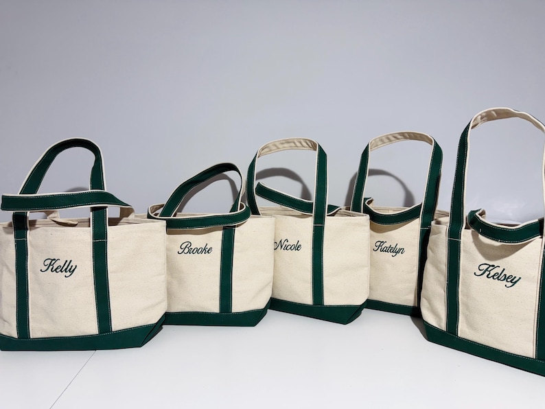 May include: Five canvas tote bags with green trim and personalized names: Kelly, Brooke, Nicole, Katelyn, and Kelsey.