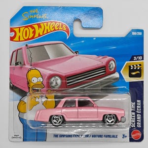 May include: A pink Hot Wheels die-cast car of The Simpsons Family Car. The packaging features Homer Simpson and the text "SCREEN TIME GRAND ÉCRAN". The car is 3/10 in the series.
