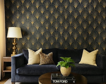 May include: A living room with a navy blue sofa, gold-toned lamp, and a round coffee table. The wall features a black and gold art deco pattern. Decorative pillows in beige and leopard print add texture. A potted plant and a book titled "TOM FORD" are on the table.