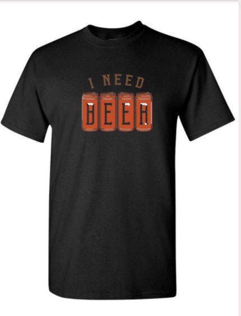 May include: Black t-shirt with the text "I NEED BEER" in brown letters above four orange beer can illustrations. The shirt is a short-sleeved crew neck.