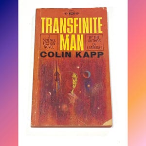 May include: Vintage paperback book titled "TRANSFINITE MAN" by Colin Kapp. The cover is predominantly orange with yellow text and a painted illustration of a man and a space scene. The book is a science fiction novel.