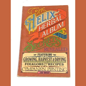 May include: A vintage book titled "The Elix Herbal Album" with a brown cover. The cover features colorful text and illustrations, including the words "Secrets Revealed" and information on growing, harvesting, and recipes.