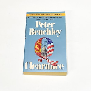 May include: A paperback book cover with a blue background. The title "Clearance" is in large white letters. The author's name, "Peter Benchley", is in large white letters above the title. The cover features a stylized image of the US Capitol building inside a red, white, and blue flag.