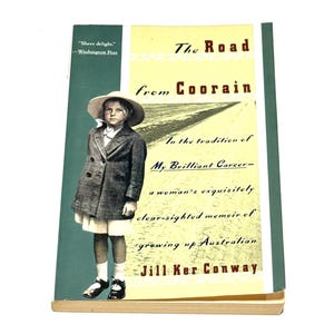 May include: A book cover for "The Road from Coorain" by Jill Ker Conway. The cover features a sepia-toned image of a young person in a coat and hat. Text includes the title, author's name, and a quote from the Washington Post.