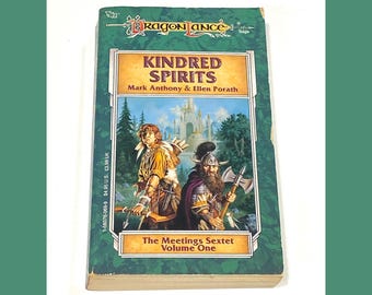 May include: A paperback book titled "Kindred Spirits" from the Dragonlance Saga series. The cover features illustrations of two characters with weapons, set against a forest and castle backdrop. The book is Volume One of The Meetings Sextet.
