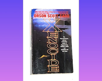 May include: A book cover with a black background and white text. The title of the book is "Xenocide" and the author is Orson Scott Card. The book is a sequel to "Ender's Game" and "Speaker for the Dead".
