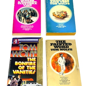 May include: Four vintage books by Tom Wolfe are displayed. The titles include "Mauve Gloves & Madmen, Clutter & Vine", "The Electric Kool-Aid Acid Test", "The Bonfire of the Vanities", and "The Painted Word". The books feature colorful covers with text and illustrations.