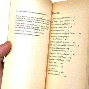 May include: Open book with text. The left page has copyright information. The right page displays a table of contents, including "Playboy Interview" and "Robert Kennedy's Prison". The book is held open by a hand.