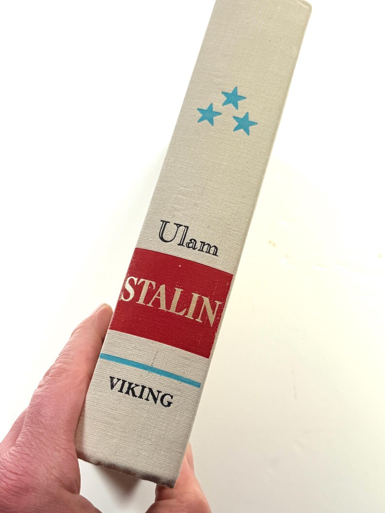Puede incluir: Lomo de libro con el t&iacute;tulo "STALIN" en blanco sobre fondo rojo. El nombre del autor, "Ulam", est&aacute; encima, y la editorial, "VIKING", debajo. Tres estrellas turquesas est&aacute;n impresas en la parte superior.