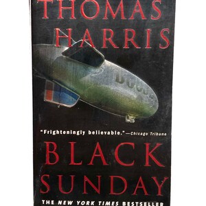 Pu&ograve; includere: Una copertina di un libro tascabile con sfondo nero e titolo rosso. Il titolo &egrave; "BLACK SUNDAY" di Thomas Harris. La copertina presenta un dirigibile con le parole "U.S." sul lato. Il testo "From the author of Hannibal and The Silence of the Lambs" &egrave; in cima alla copertina. Il testo "The New York Times Bestseller" &egrave; in fondo alla copertina.