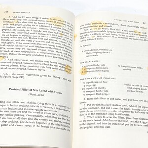 May include: A close-up of a recipe for pan-fried sole fillets with carom seeds. The recipe includes instructions for marinating the fish in a lemon juice marinade and then coating it in a spicy breadcrumb mixture. The recipe also includes a list of ingredients and instructions for preparing the marinade and the breadcrumb coating.
