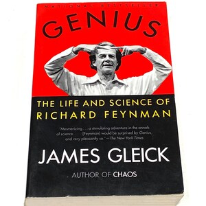 May include: A hardcover book titled "GENIUS" with a red cover and a portrait of a man. The book is about the life and science of Richard Feynman, written by James Gleick, and is a National Bestseller.