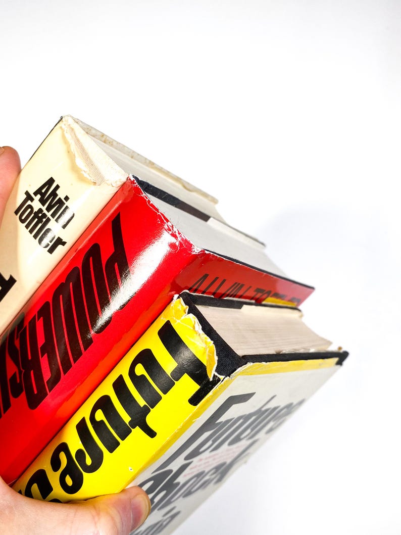 a hand holding a stack of books in front of a white background