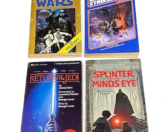 May include: Four paperback books from the Star Wars franchise. The books are titled "Star Wars", "The Empire Strikes Back", "Return of the Jedi", and "Splinter of the Mind's Eye".
