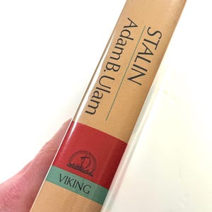 Puede incluir: Un libro de tapa dura titulado "STALIN" de Adam B. Ulam. El lomo del libro es de color beige con detalles en rojo y verde. Se ve el logotipo de la editorial y la palabra "VIKING".
