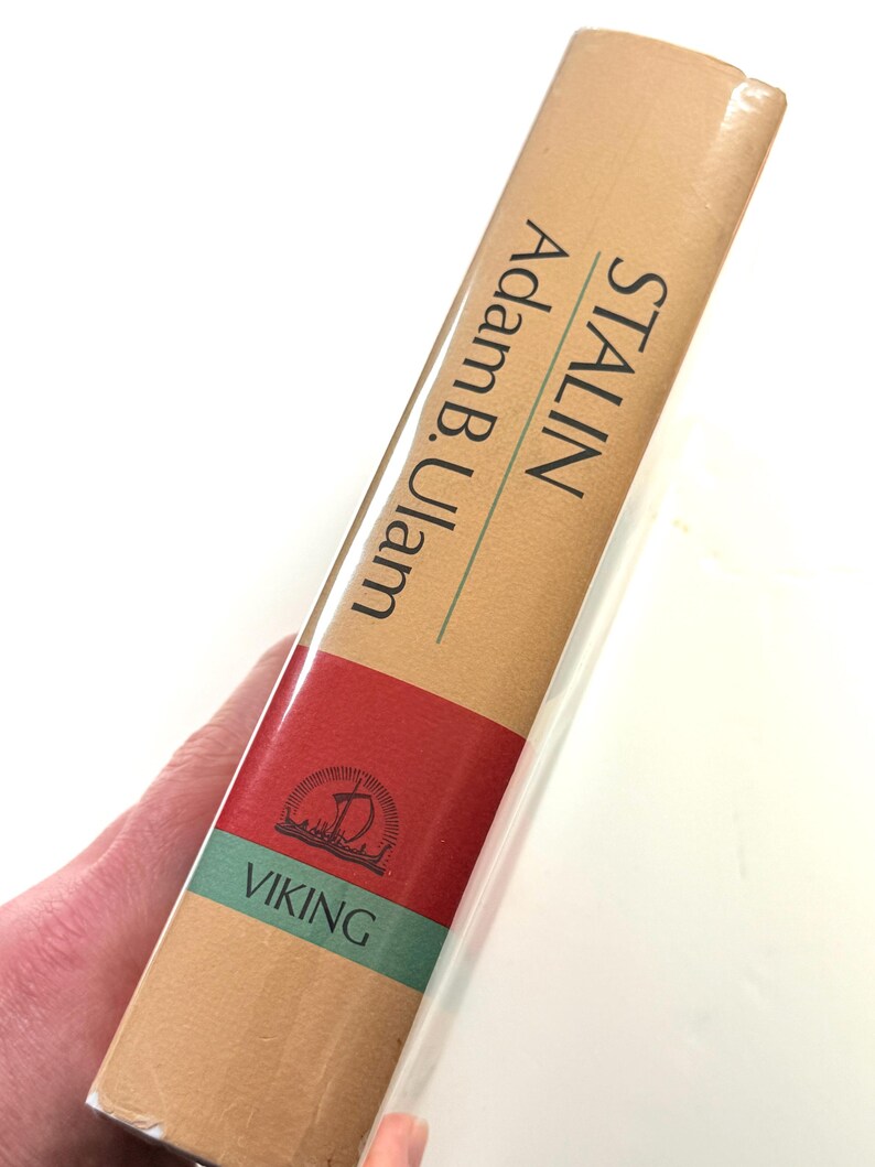Puede incluir: Un libro de tapa dura titulado "STALIN" de Adam B. Ulam. El lomo del libro es de color beige con detalles en rojo y verde. Se ve el logotipo de la editorial y la palabra "VIKING".