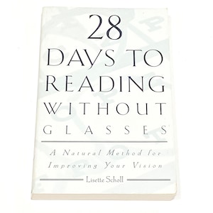 May include: A white paperback book titled 28 Days to Reading Without Glasses: A Natural Method for Improving Your Vision by Lisette Scholl. The cover features black text in a serif font with a faint, light gray background pattern of letters.
