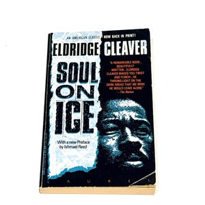 May include: A paperback book titled "Soul on Ice" by Eldridge Cleaver. The cover features a portrait of a man and the book's title in large, bold letters. The book is an American classic, now back in print.