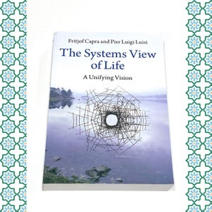 May include: A hardcover book titled "The Systems View of Life: A Unifying Vision" by Fritjof Capra and Pier Luigi Luisi. The cover features a landscape with a lake and a geometric design in the center. The book is white with a colorful border.