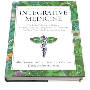 May include: A hardcover book titled "INTEGRATIVE MEDICINE" with a green cover featuring botanical illustrations. The book's title is in large, bold letters, and the cover includes the text "The Patient's Essential Guide to Conventional and Complementary Treatments".