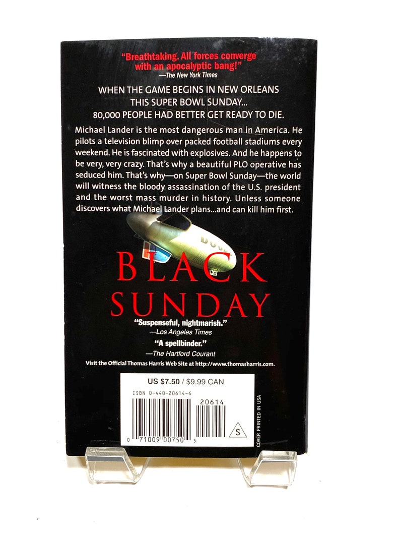 Pu&ograve; includere: Una copertina di un libro tascabile per il romanzo "Black Sunday" di Thomas Harris. La copertina presenta un'immagine in bianco e nero di un dirigibile con il titolo "Black Sunday" in grandi lettere rosse e in grassetto. La descrizione del libro include citazioni di recensioni, come "Suspenseful, nightmarish." e "A spellbinder."