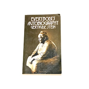 May include: A vintage paperback book titled "Everybody's Autobiography" by Gertrude Stein. The cover features a sepia-toned illustration of a woman sitting with her head down.
