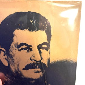 Puede incluir: Primer plano de una portada de libro con un retrato en blanco y negro de un hombre con un bigote prominente. El fondo es un degradado de oro y beige. El t&iacute;tulo es parcialmente visible en rojo.