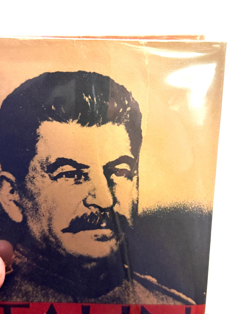 Puede incluir: Primer plano de una portada de libro con un retrato en blanco y negro de un hombre con un bigote prominente. El fondo es un degradado de oro y beige. El t&iacute;tulo es parcialmente visible en rojo.