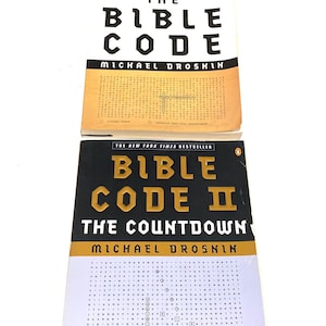 May include: Two books titled "The Bible Code" and "Bible Code II: The Countdown" by Michael Drosnin. The first book has a white cover with black text, and the second has a black cover with gold text. Both are labeled "The New York Times Bestseller."